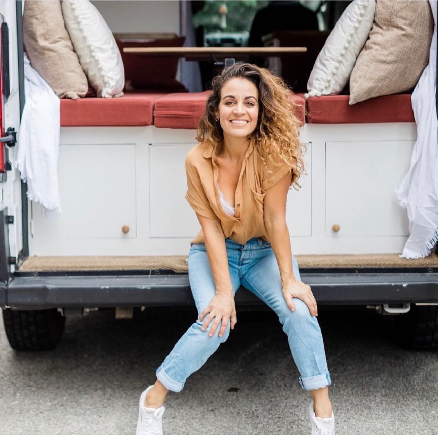Jenn Dieas seated on the back step of a converted camper van