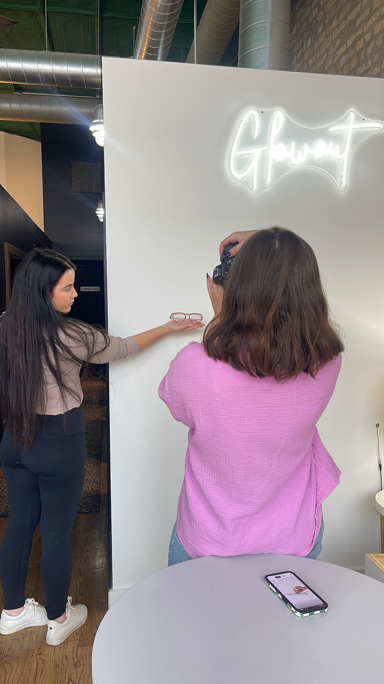 A content shoot in production — photographer framing a product against a white wall