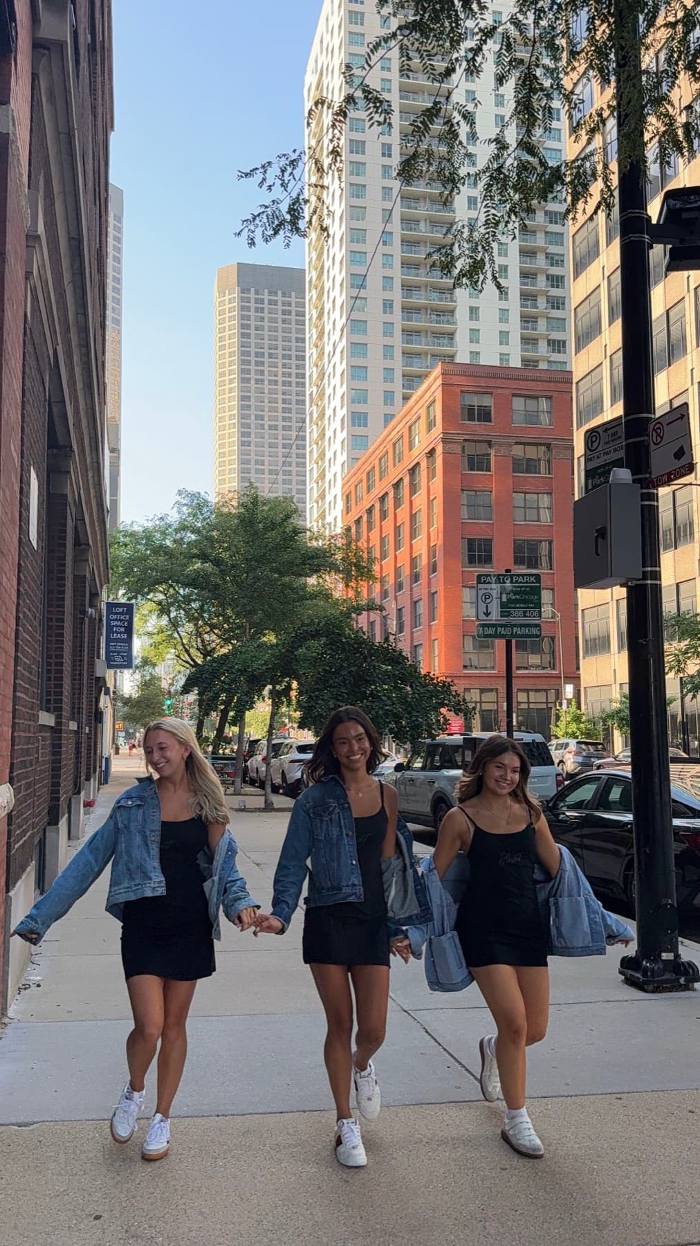 Three women in matching branded dresses walking a Chicago sidewalk together